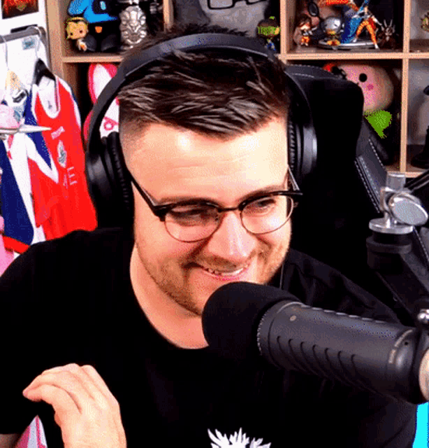a man wearing headphones and glasses is smiling at the microphone