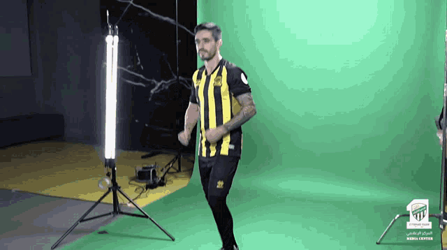 a man in a yellow and black striped shirt stands in front of a green background