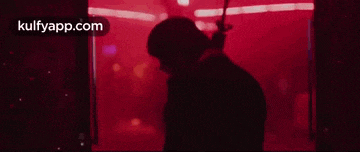 a man in a suit is holding a gun in a red room .