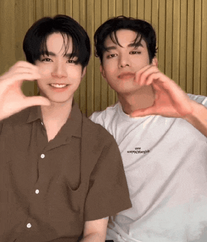 two young men are making a heart shape with their hands and one of them is wearing a shirt that says " happy margiel "