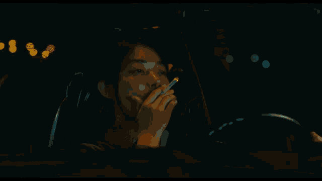 a person 's hands holding a cigarette and a lighter in the dark