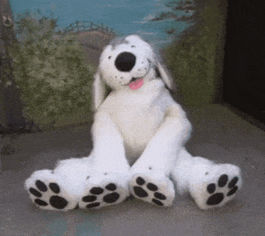a stuffed dog is sitting on the ground with its tongue out
