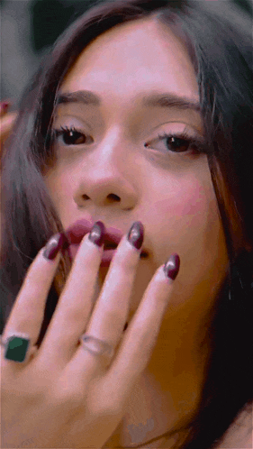 a close up of a woman 's face with purple nails