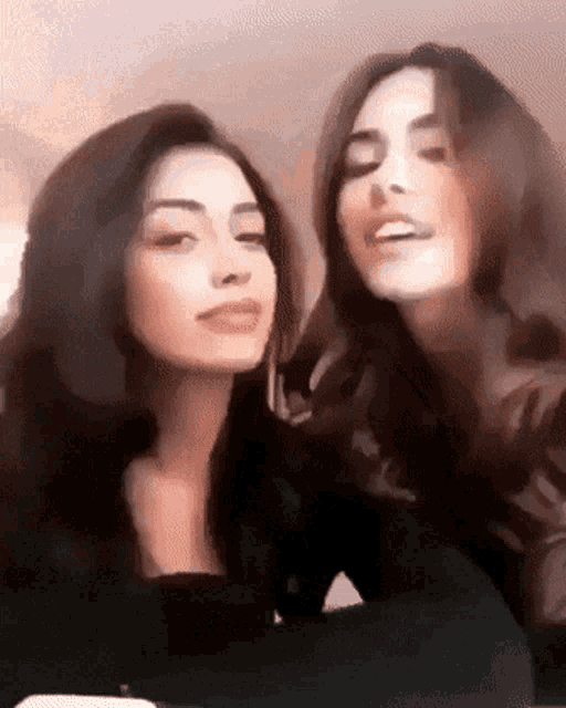 two women are standing next to each other and smiling .