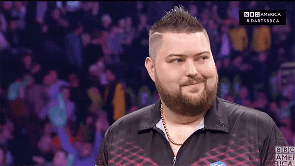 a man with a beard wearing a bbc america shirt smiles