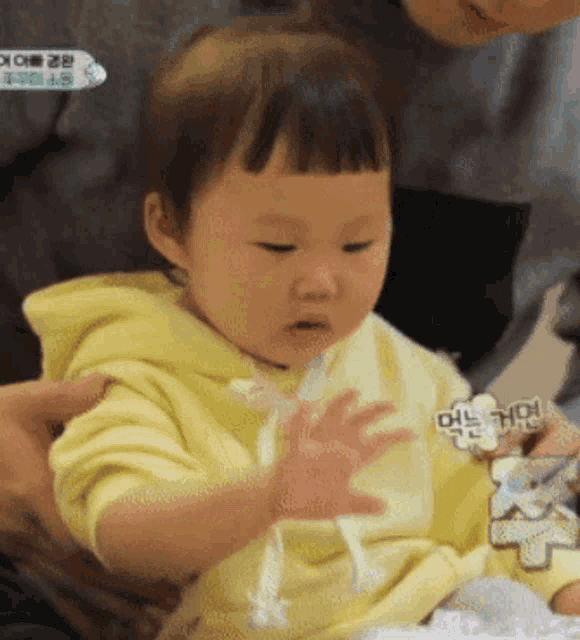 a baby in a yellow hoodie is being held by a person