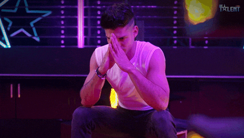 a man covering his face with his hands in front of a talent sign