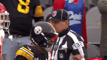 a referee with the number 132 on his shirt talks to a football player