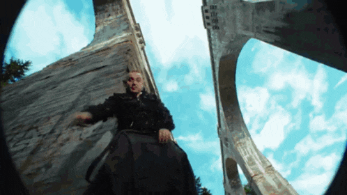 a man is standing in front of a bridge and looking up at the sky