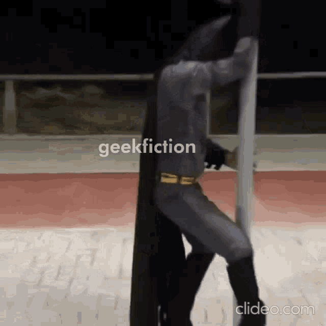 a man in a batman costume is holding onto a pole .