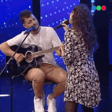a man is playing a guitar and a woman is singing into a microphone