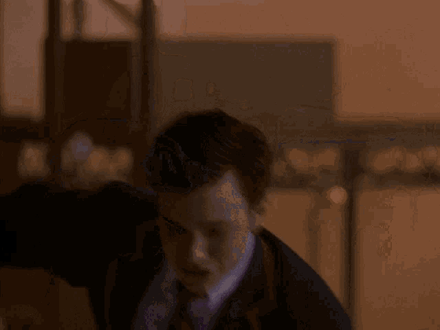 a man in a suit and tie is standing in a dark room with his arms outstretched