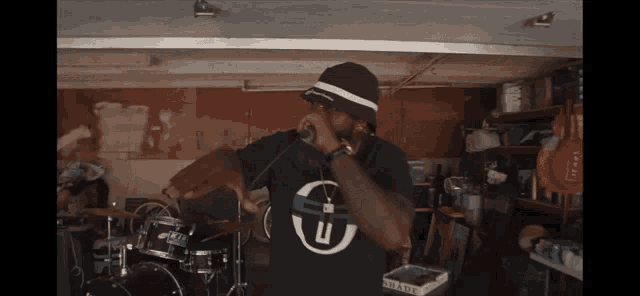 a man wearing a black shirt with the letter u on it is singing into a microphone