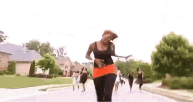 a woman is walking down a street with a bunch of people .