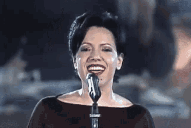 a woman is singing into a microphone in a dark room