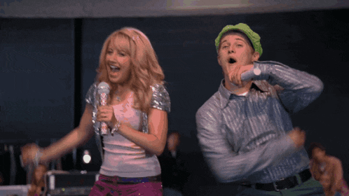 a woman singing into a microphone next to a man with his mouth open