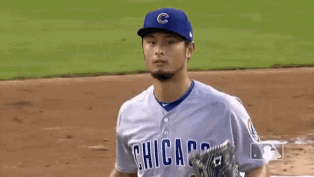 a baseball player for the chicago cubs is standing on the field with his arms outstretched .