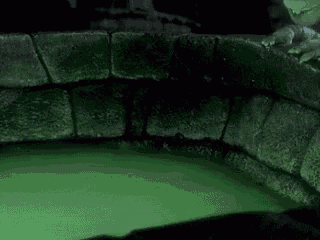 a large rock is floating in a green liquid in a dark room .