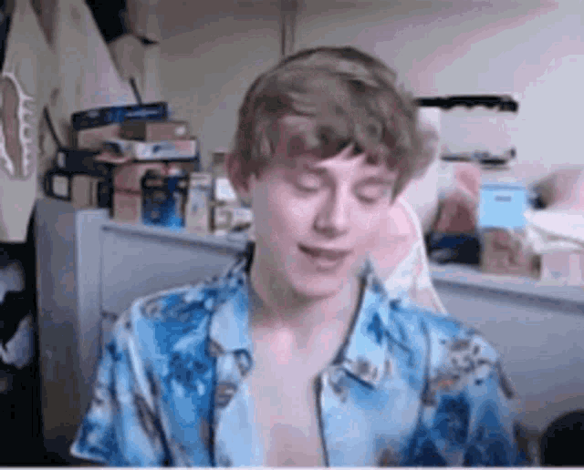 a man in a blue shirt is sitting in a room