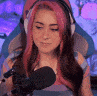 a woman with pink hair is sitting in a chair in front of a microphone .