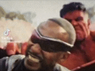 a man wearing goggles is holding another man 's head .