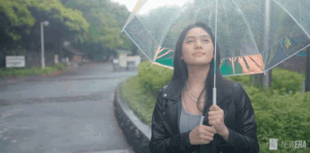 a woman holding a clear umbrella with the newera logo on the bottom