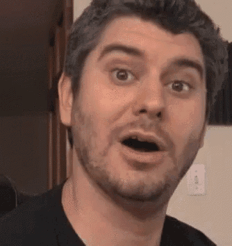 a man with a beard and a black shirt is making a funny face .