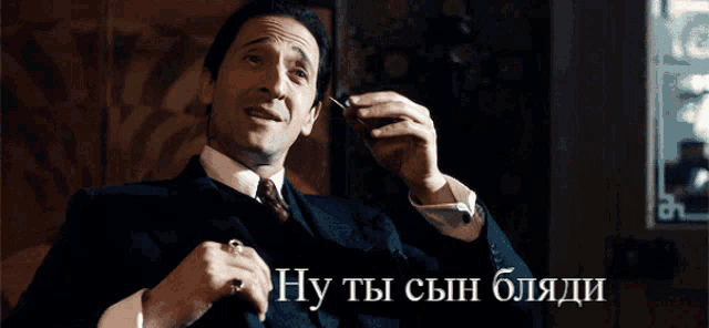 a man in a suit and tie smoking a cigarette with a caption in russian