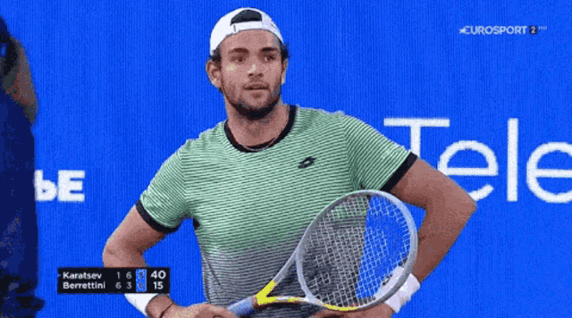 a man is holding a tennis racquet in front of a blue background with the word tele on it
