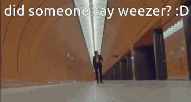 a woman walking down a hallway with the words " did someone say weezer " above her