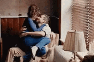 a man is carrying a woman on his shoulders while they are kissing .