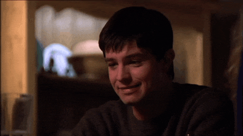 a man in a black sweater is smiling and looking down
