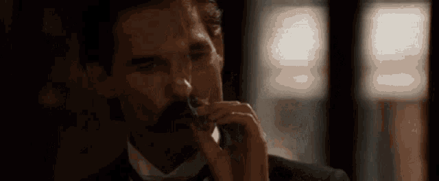 a man in a suit and tie is drinking from a glass .