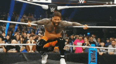 a wrestler is jumping in the air while standing in a wrestling ring .