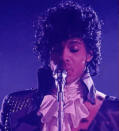 a man singing into a microphone with a purple background