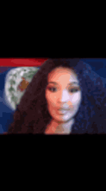 a woman with curly hair is standing in front of a belice flag .