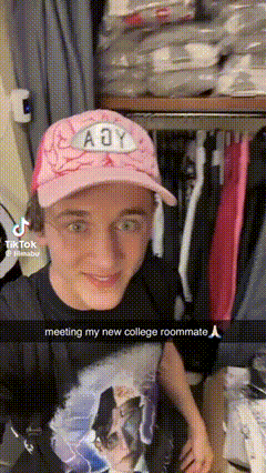 a young man wearing a pink hat and a black shirt is standing in front of a closet .