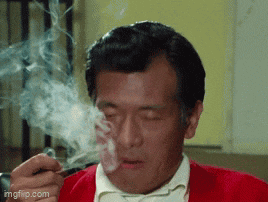 a man in a red jacket is smoking a cigarette with his eyes closed