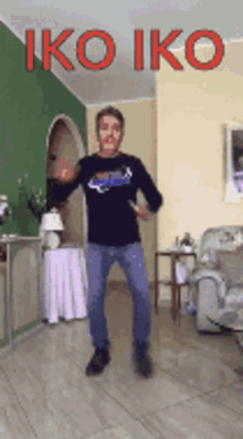 a man in a black shirt is dancing in a living room with the words iko iko written above him