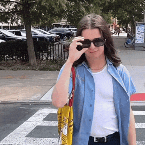 a woman wearing sunglasses holds a yellow bag that says " i love you "