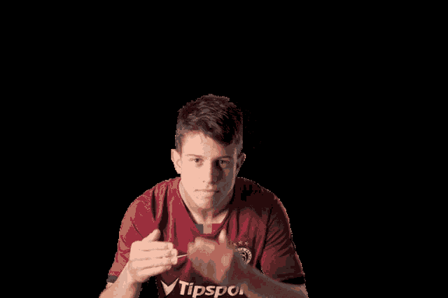 a man wearing a red tipsport shirt holds his head