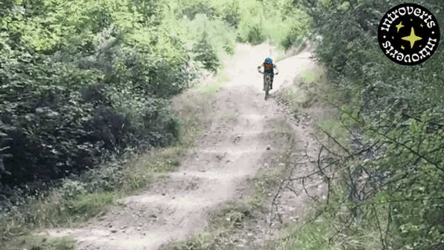 a person riding a bike down a dirt road with a logo that says introverts start