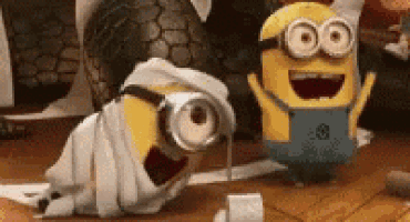 two minions are playing with toilet paper on the floor and one of them is wrapped in a towel .