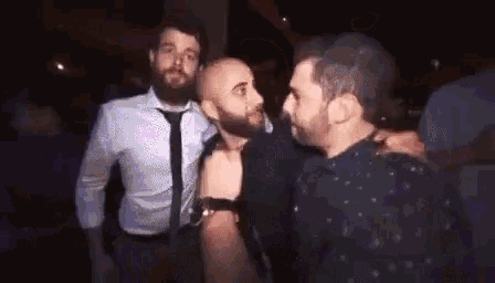 a group of men are standing next to each other in a dark room .