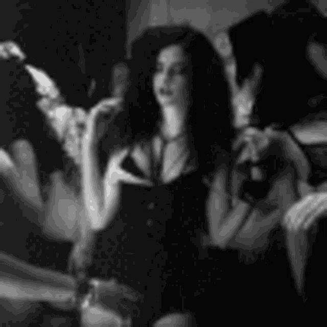 a woman in a black dress is sitting in front of a mirror holding a wine glass .