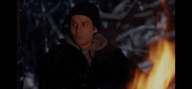 a man standing in front of a fire with the words " so now we 're battling the elements too "
