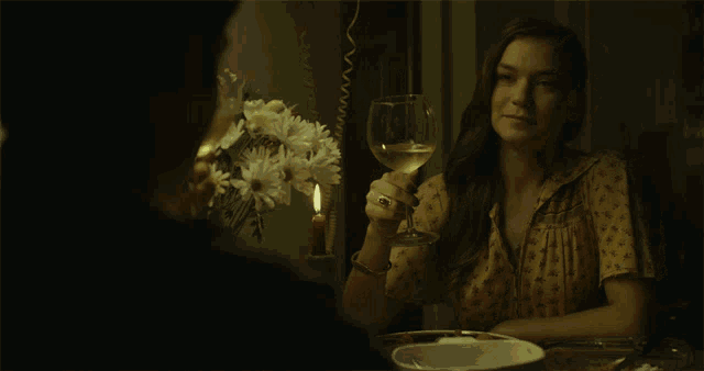 a woman holds a glass of wine in front of a man