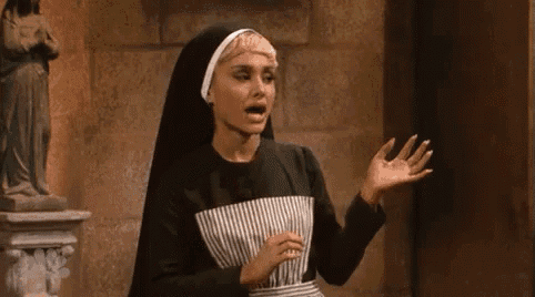 a woman in a nun costume is standing in front of a statue of a woman .