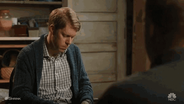 a man in a blue cardigan is talking to another man in a black shirt ..