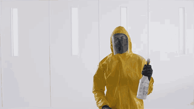 a man in a yellow protective suit is holding a bottle